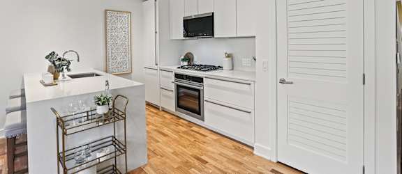 A kitchen with white cabinets and a white island with a sink.