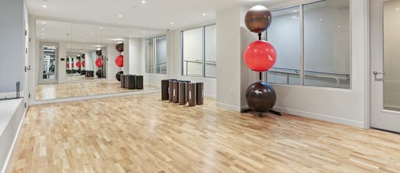 A room with wooden floors and a red balloon on a black sphere.