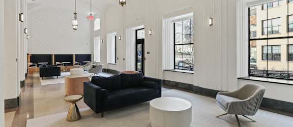 A large, open living room with a black couch, a white coffee table, and a large window.