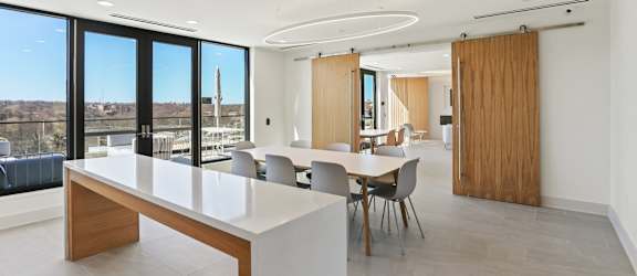 A modern dining room with a long table and chairs.