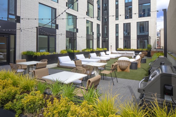 an outdoor patio area with tables and chairs and a building in the background at The Weidler in Portland, OR 97209