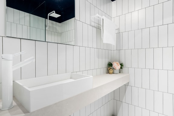 a white tiled bathroom with a sink and a mirror