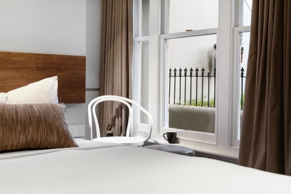 a hotel room with a bed and a chair and a window