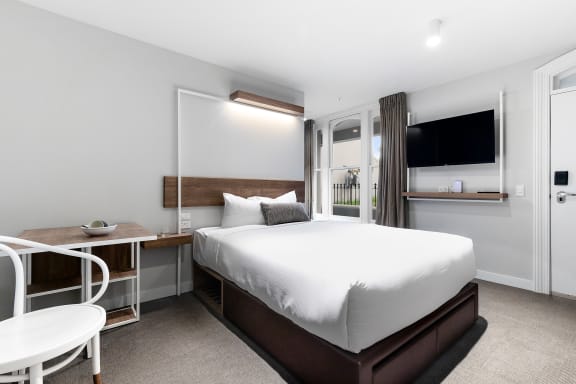 a bedroom with a bed and a desk and a television