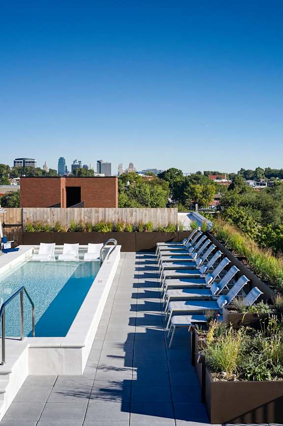 A rooftop pool with sun loungers and a view of the city.