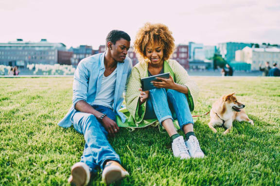a man and woman sitting on the grass looking at a tablet at The Hendrix, Atlanta, GA, 30329