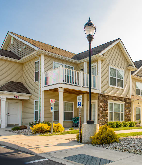 Exterior view of apartment buildings showing private patios and balconies and a streetlamp lighting the off-street parking and sidewalks