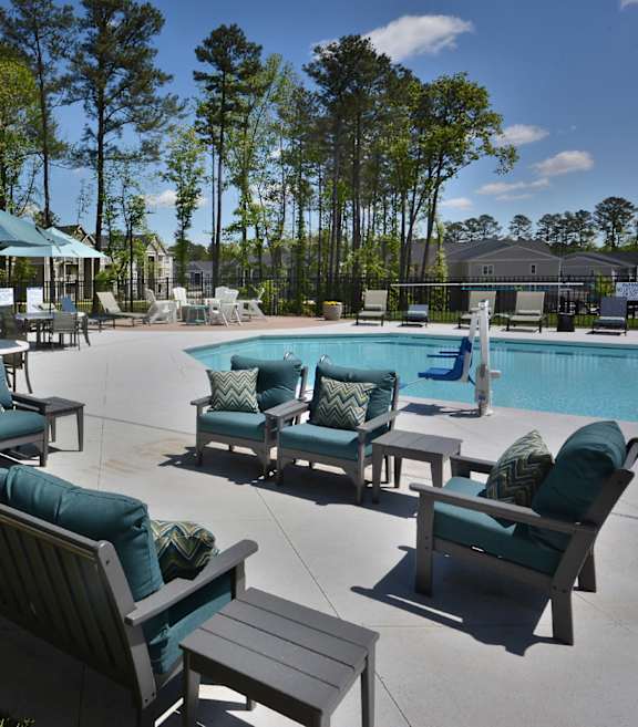 A pool area with chairs and a building in the background.
