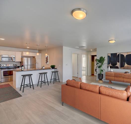 A modern living room with a bar area and a kitchen in the background.