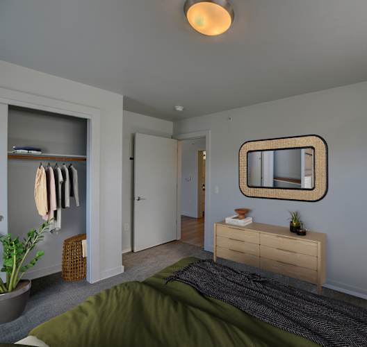 A bedroom with a bed, dresser, mirror, and closet.