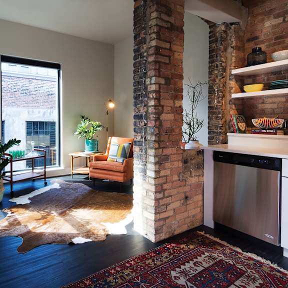 A living room with a cowhide rug and a brick wall.