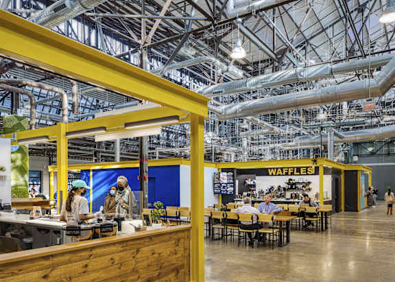 A waffle shop is located inside a large building with a lot of pipes.