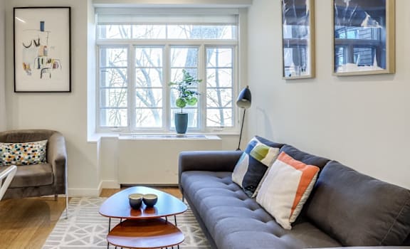 A living room with a black couch, a white chair, and a coffee table.