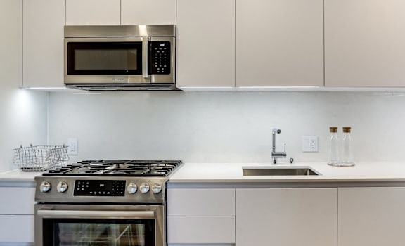A modern kitchen with a stove, microwave, and white cabinets.