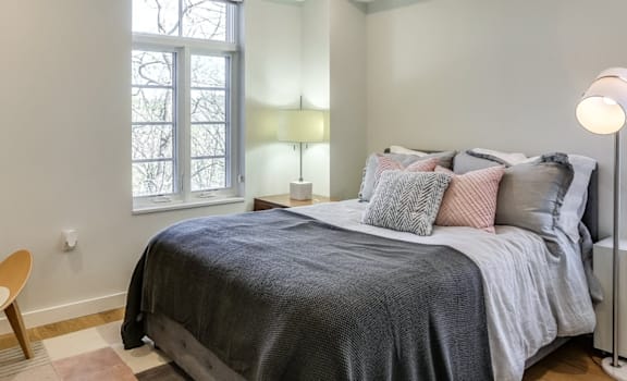 A bedroom with a bed, chair, and window.