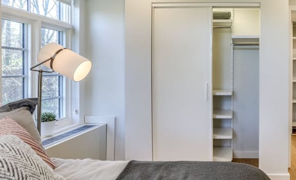 A bedroom with a bed, a window, and a lamp.