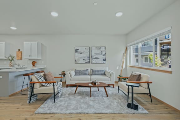A living room with a grey rug and a white couch.