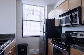 a kitchen with a stove refrigerator and microwave  and a window