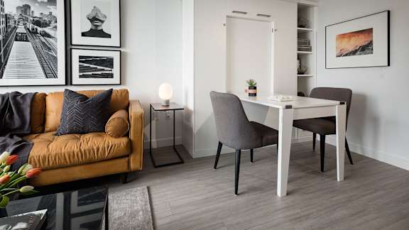 A living room with a brown couch, a white table, and a grey chair.