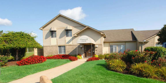 a club house with a sidewalk and lawn in front of it