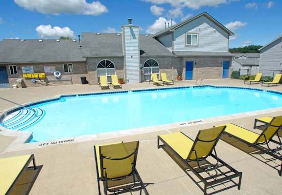 a large swimming pool with yellow chairs around it
