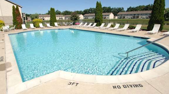 a swimming pool with chairs and a no diving sign on the side of a resort