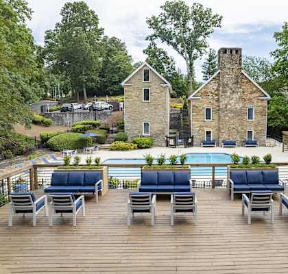 a pool with blue lounge chairs on a deck next to a stone building