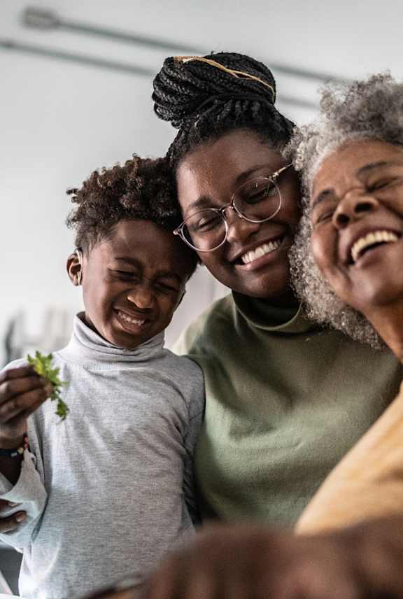 Three people are laughing together in a kitchen.