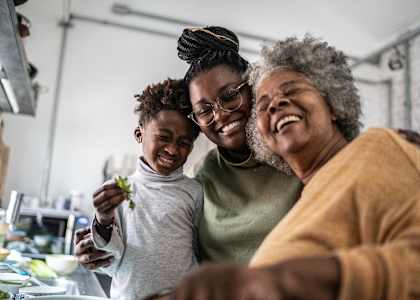 Three people are laughing together in a kitchen.