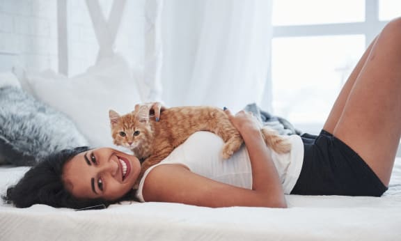 Woman laying on a bed with a cat at Brookwood at Islip in Islip, NY 11751