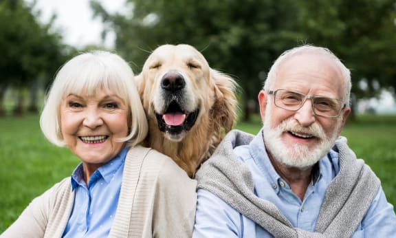 an older couple and their dog sitting on the grass at Brookwood at Oakdale 55+, Oakdale