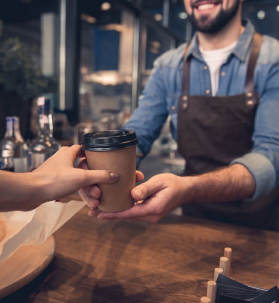 a man handing a cup of coffee to a woman at a coffee shop at Urban Crest Apartments, Texas, 78209
