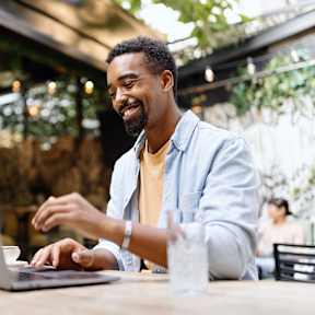 A man is typing on a laptop in a cafe.at The Garden District Apartments, Germantown, TN 38138