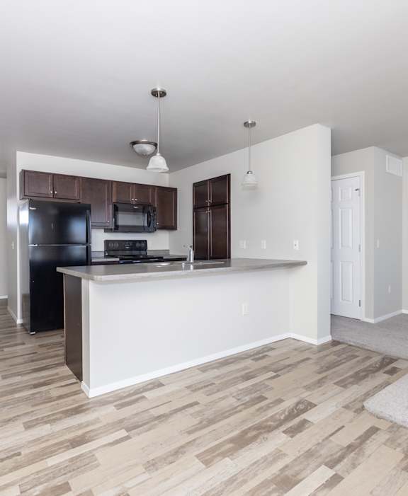 A kitchen with a white countertop and wooden flooring.