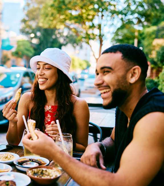 Three people are sitting at a table eating food.