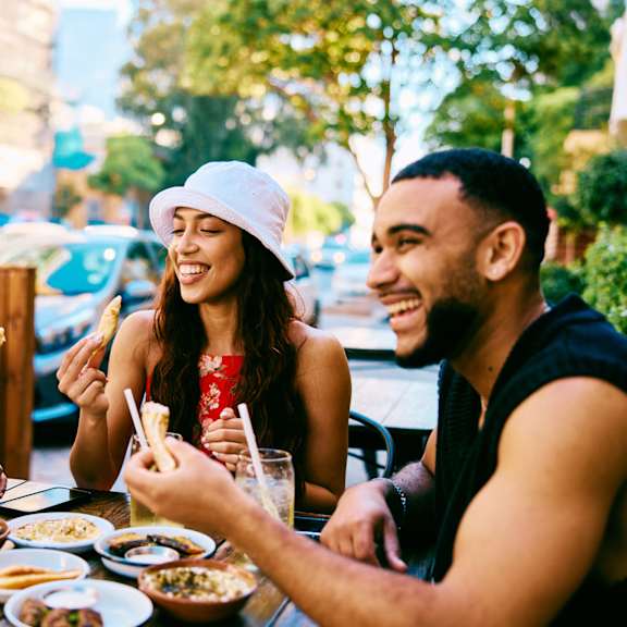 Three people are sitting at a table eating food.