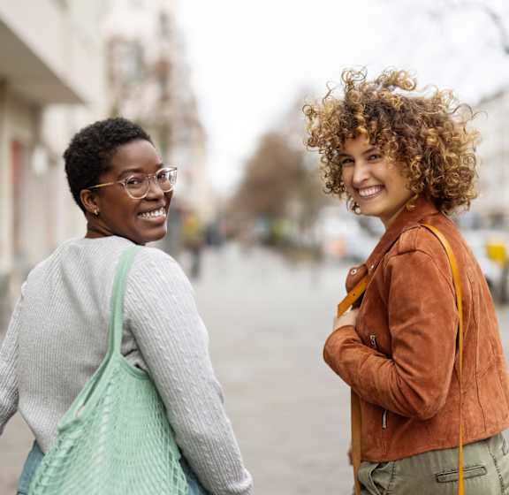 Two women are walking on a street.