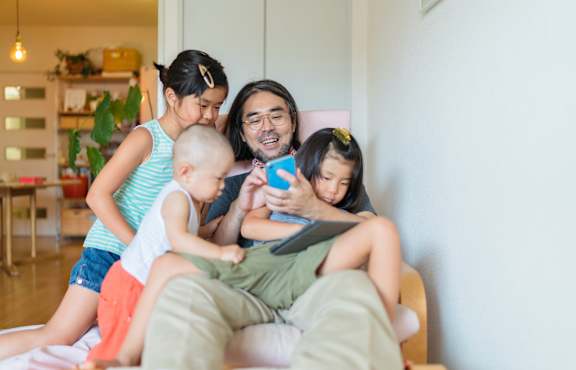 A man is reading a book to two children on a couch.