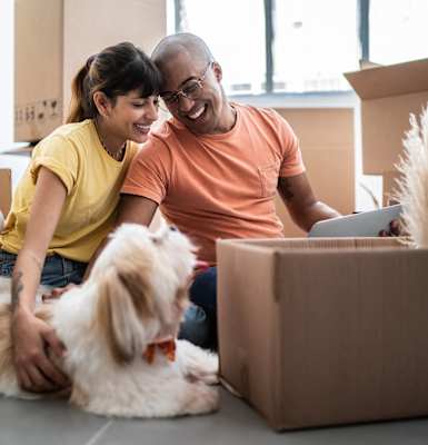 a man and woman sitting on the floor with a dog and a laptop