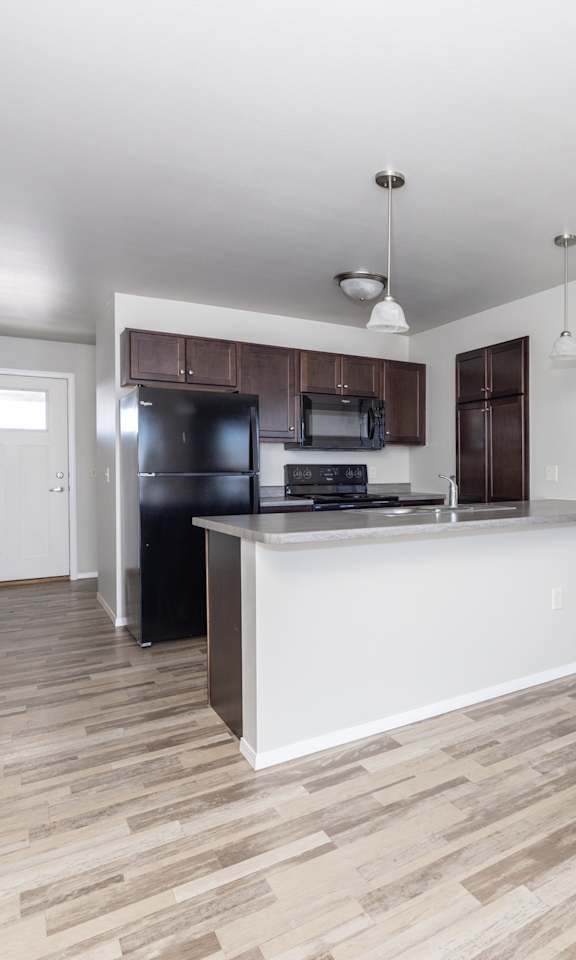 A kitchen with a white countertop and wooden flooring.