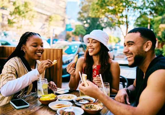 Three people are sitting at a table eating food.