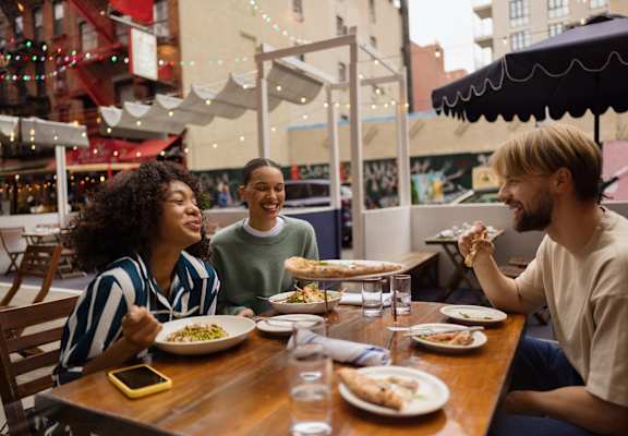 A group of people enjoying a meal together at an outdoor restaurant.