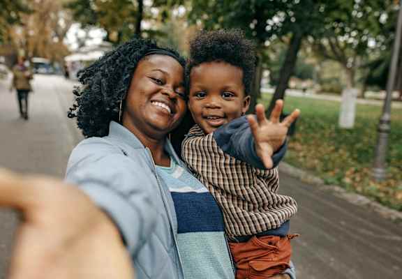 A woman and a child are taking a selfie in a park.