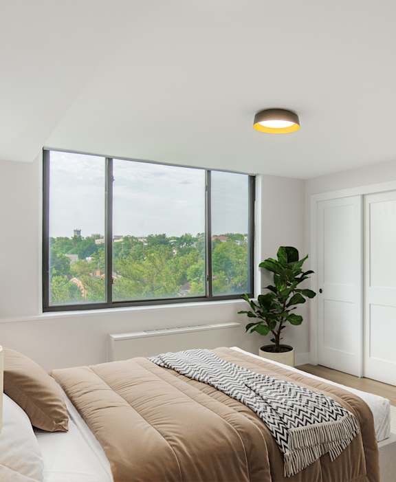 A bedroom with a large bed and a view of trees outside the window.