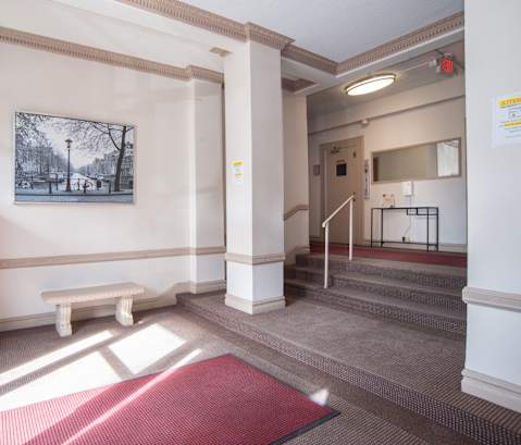 a lobby with a red rug and a bench and a painting on the wall