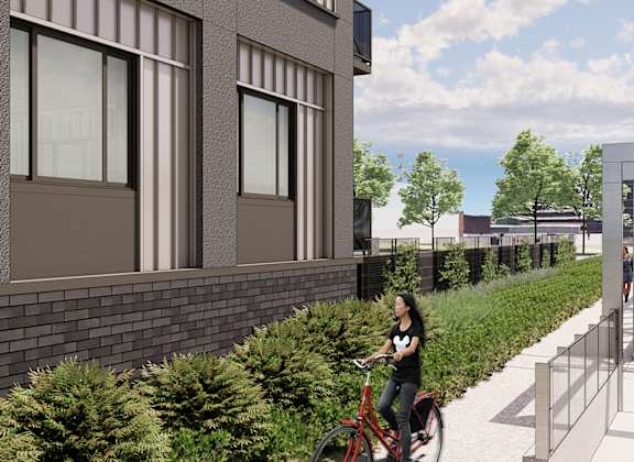 a woman riding a bike down a sidewalk next to a building