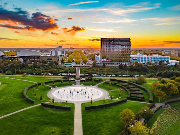 A beautiful sunset view of a park with a fountain in the center. at The Woodlands Apartments, Milton Keynes