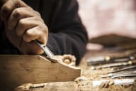 a person carving a piece of wood with a knife