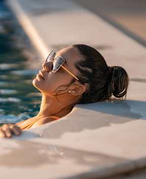 A woman in sunglasses is relaxing in a pool.