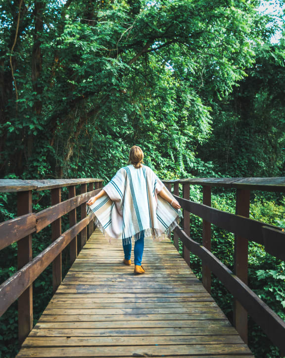 a woman walking across a bridge in the woods at The Bella at Westchester, Midlothian